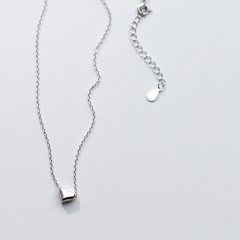 Silver necklace with a heart pendant on a light gray background