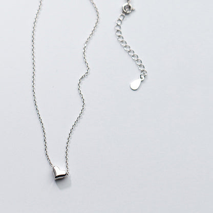 Silver necklace with a heart pendant on a light gray background