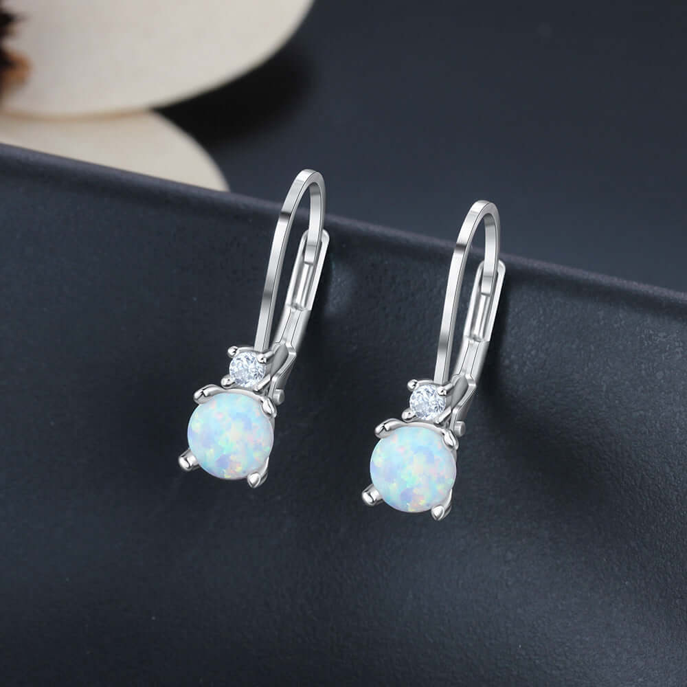 Silver earrings with opal stones on a dark surface