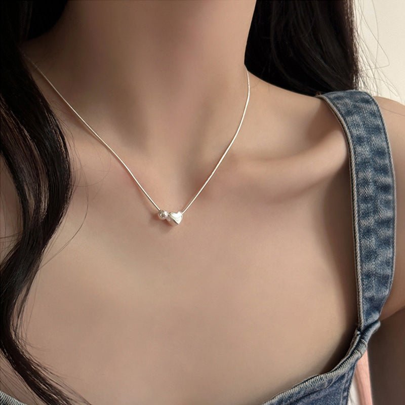 Necklace with a silver heart pendant on a mannequin wearing a denim top.