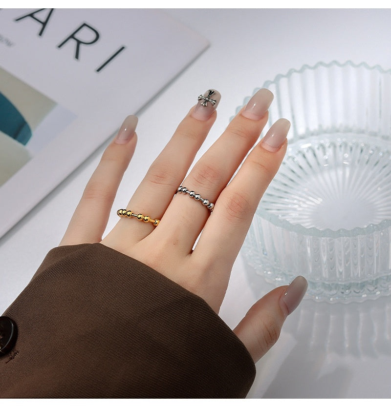 Person wearing the minimalist gold-plated beaded fidget ring on their finger in a stylish office or home environment.