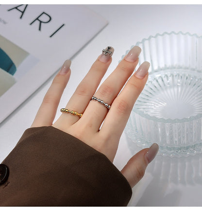 Person wearing the minimalist gold-plated beaded fidget ring on their finger in a stylish office or home environment.