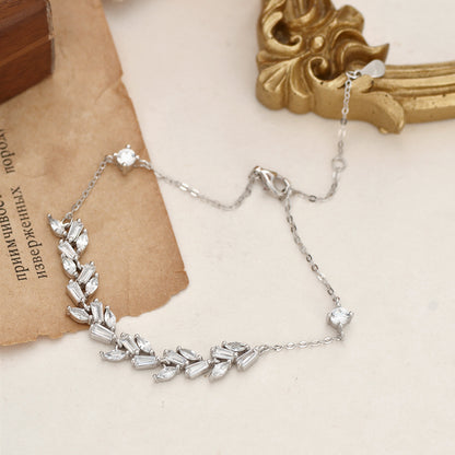 Silver bracelet with leaf-shaped crystals on a beige and white surface.