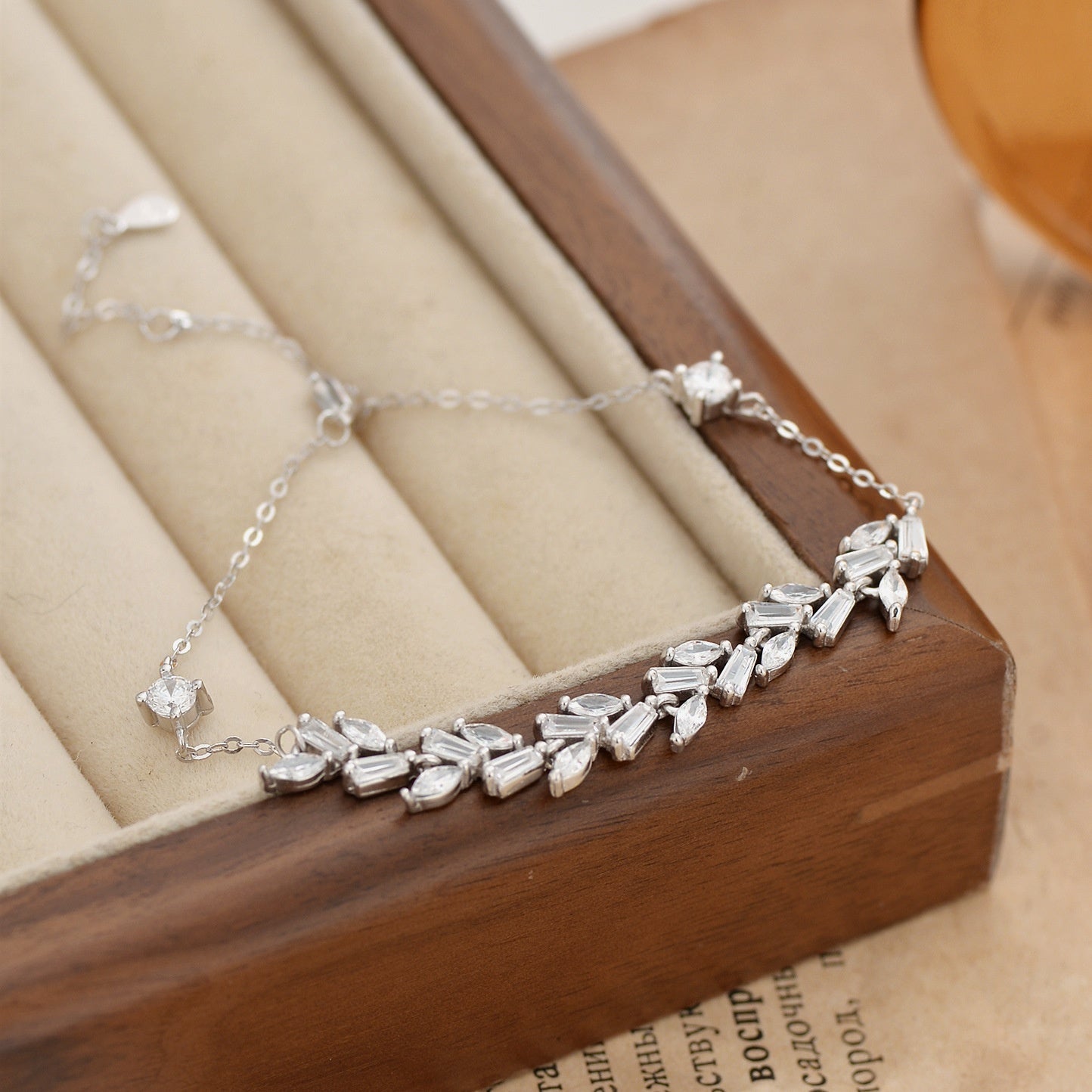 Silver bracelet with wheat wave shaped stones on a wooden jewelry box.