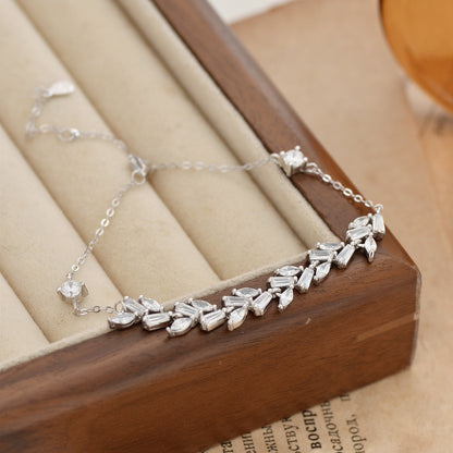 Silver bracelet with wheat wave shaped stones on a wooden jewelry box.